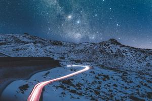 Timelapse of cars driving through the mountains with starry sky