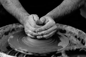 A person shaping clay by hand on a pottery wheel